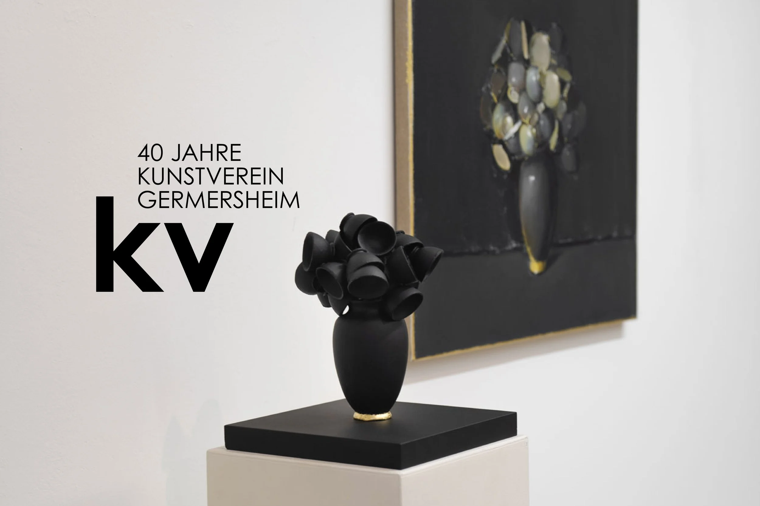 Ein Kunstwerk, das auf einem schwarzen Sockel steht, besteht aus einer schwarzen Vase mit mehreren schwarzen, konisch geformten Gegenständen. Im Hintergrund ist ein Text sichtbar, der lautet: "40 Jahre Kunstverein Germersheim".