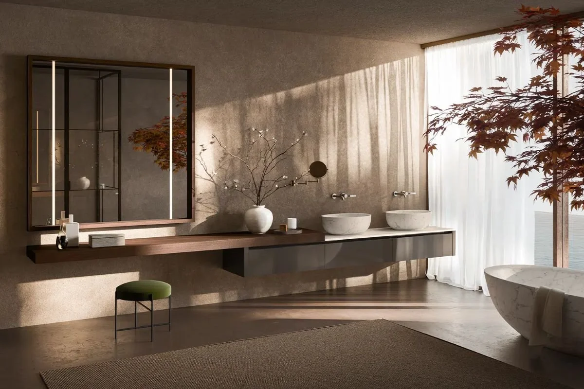 A modern bathroom with a large window, a floating vanity with two vessel sinks, a large mirror, a green stool, and a bathtub, with natural light streaming in and a tree visible outside.