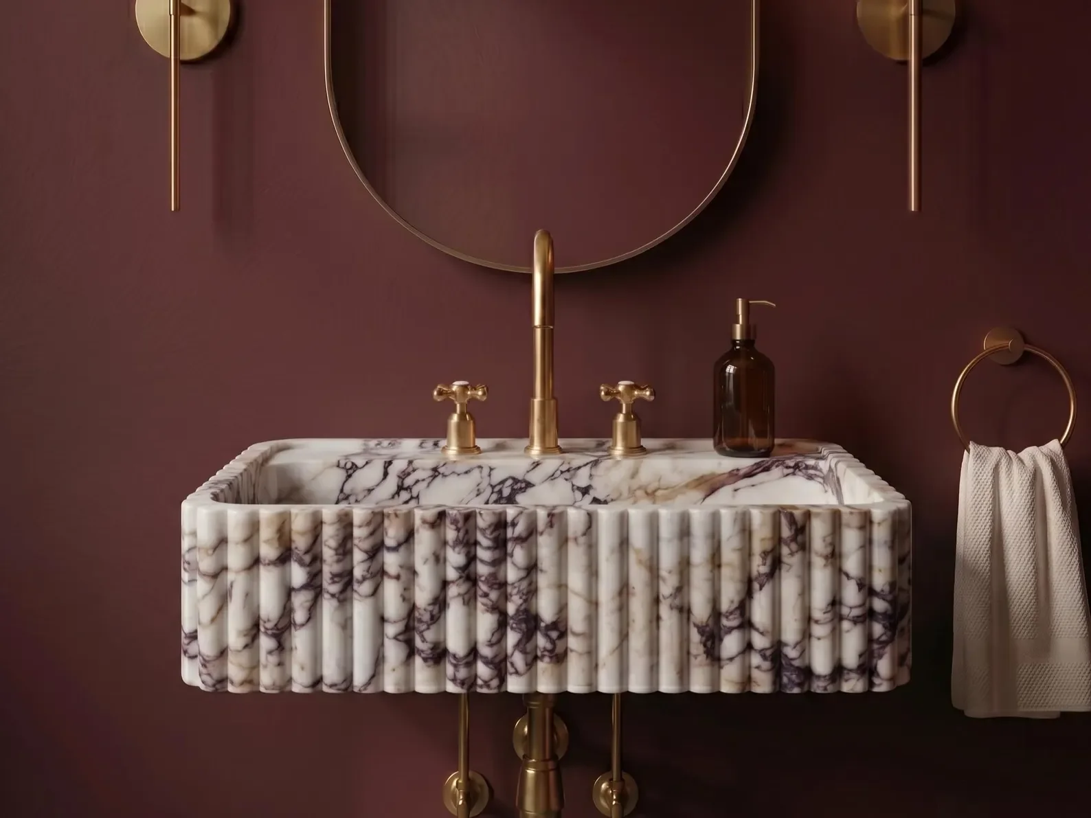 Marble bathroom sink with gold fixtures, a mirror above it, a brown wall background, and a towel hanging on a gold ring to the right.