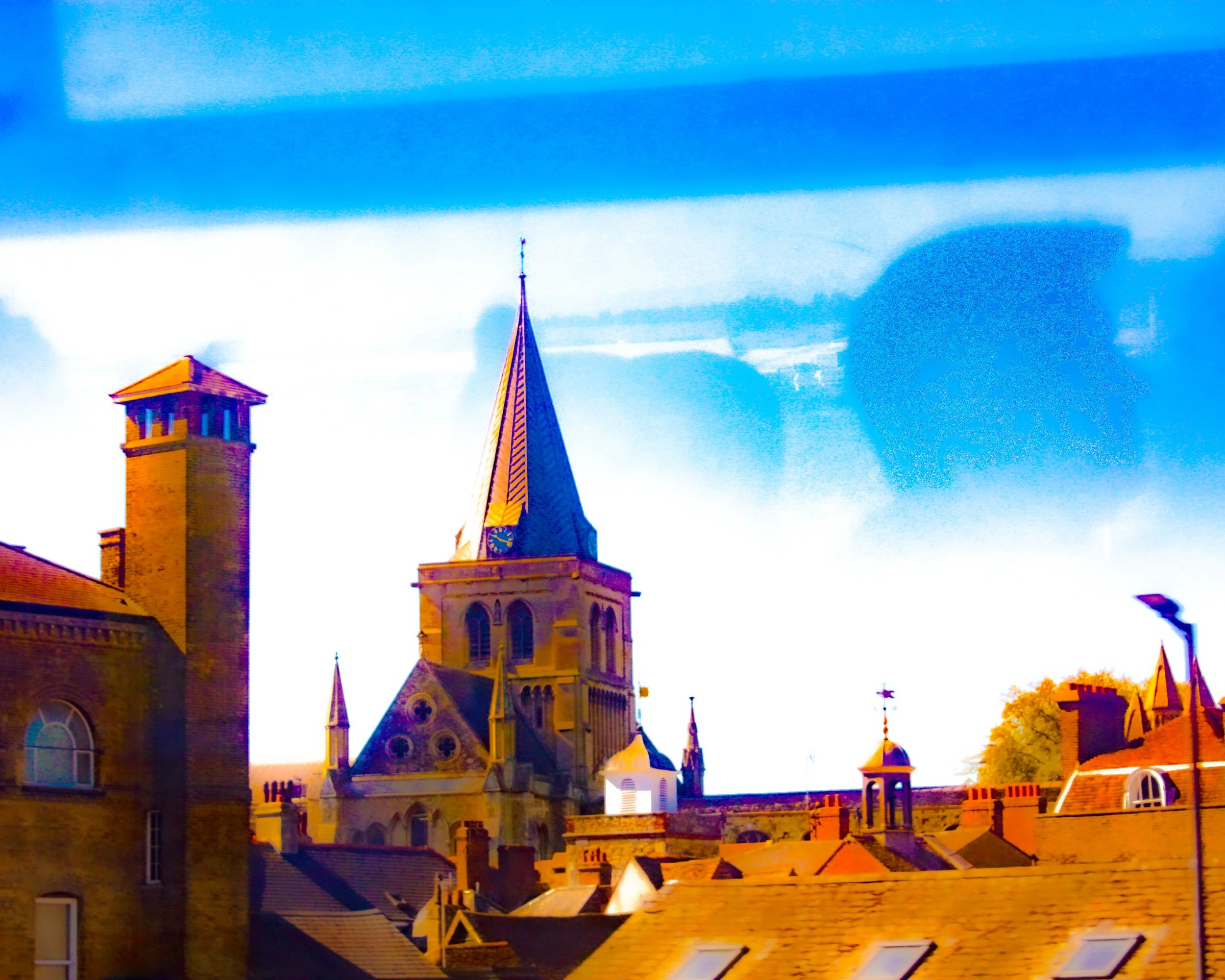 A photo of a historic building with a clock tower and multiple steeples, taken during sunset with a vibrant blue sky and some clouds.