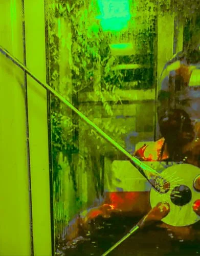 A person cleaning a glass door with a squeegee in a brightly lit environment.