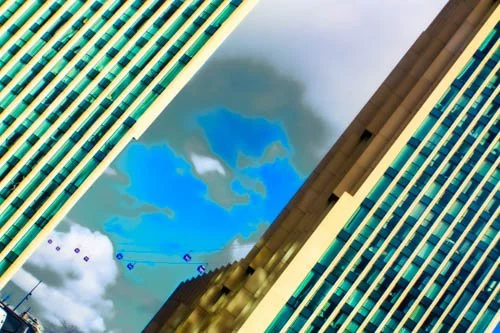 Reflection of clouds and blue sky in the glass windows of two modern high-rise buildings