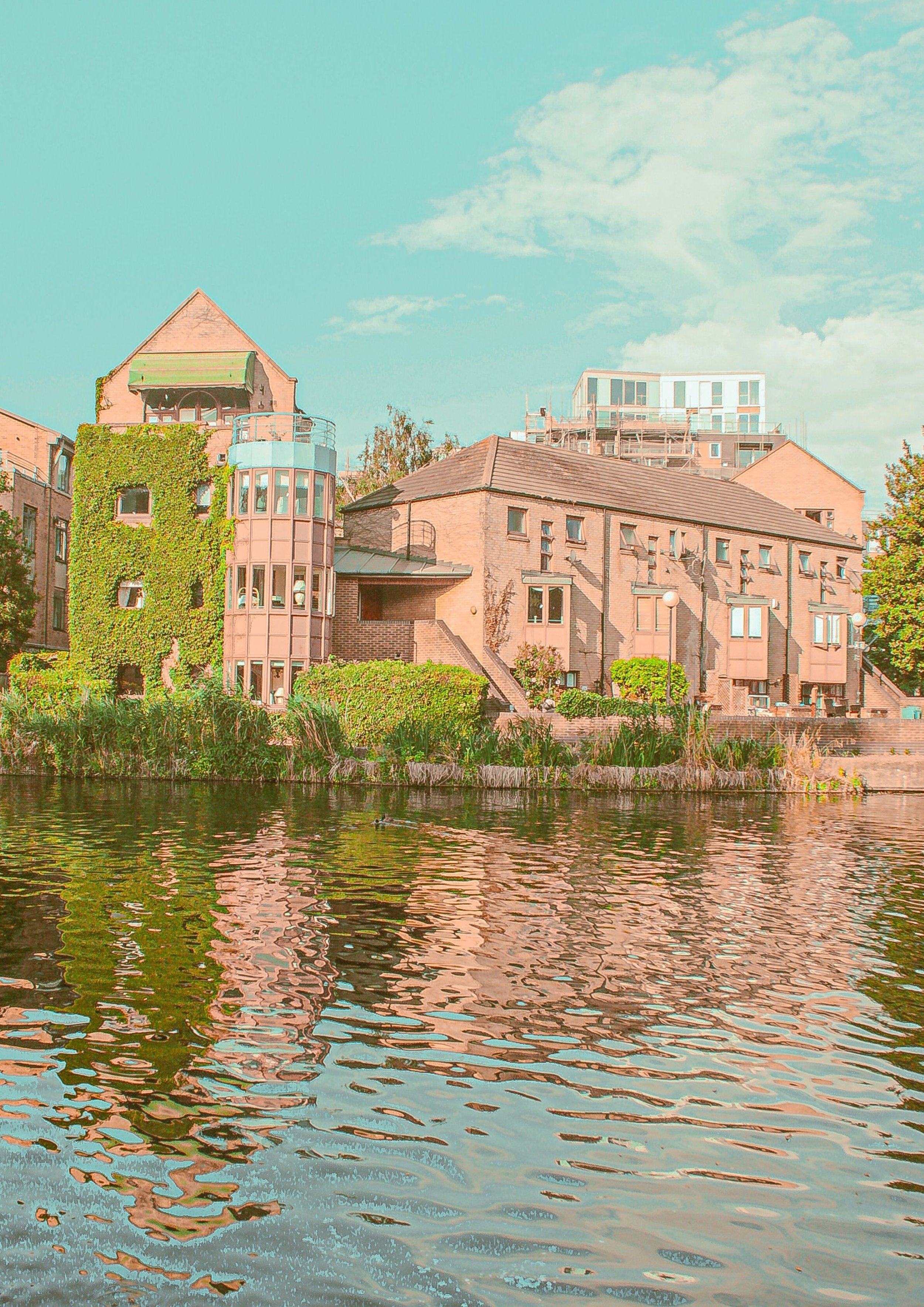 City buildings by a river with reflections in the water on a sunny day.