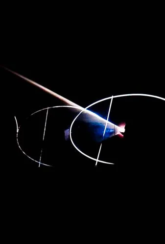 A plasma ball with colorful electric discharges inside and a person's hand touching its surface, creating streaks of light.