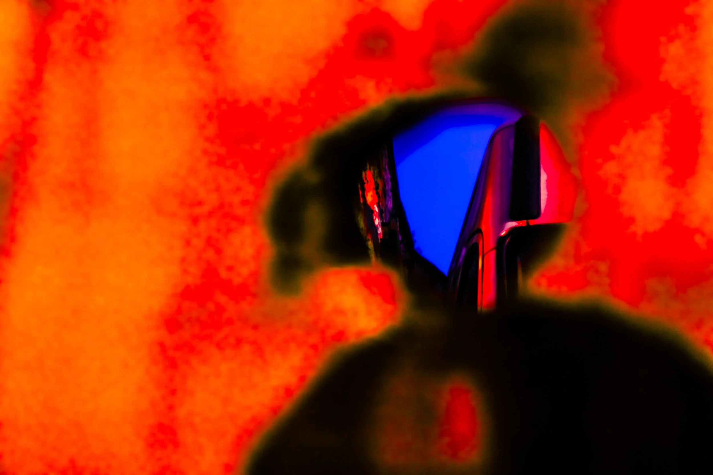 Close-up of a computer mouse with a reflective surface, set against a highly saturated, red-orange background.