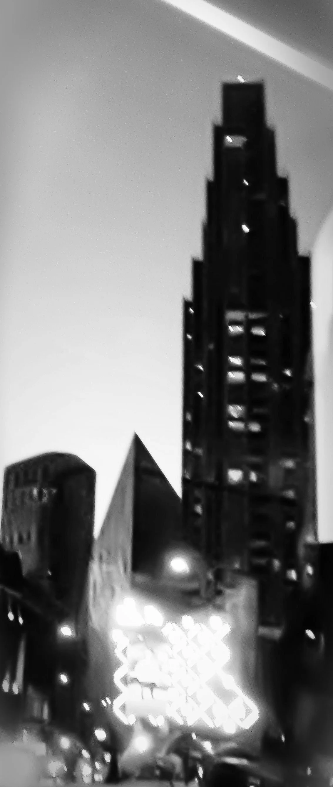 Nighttime city street with tall buildings and bright decorative lights.