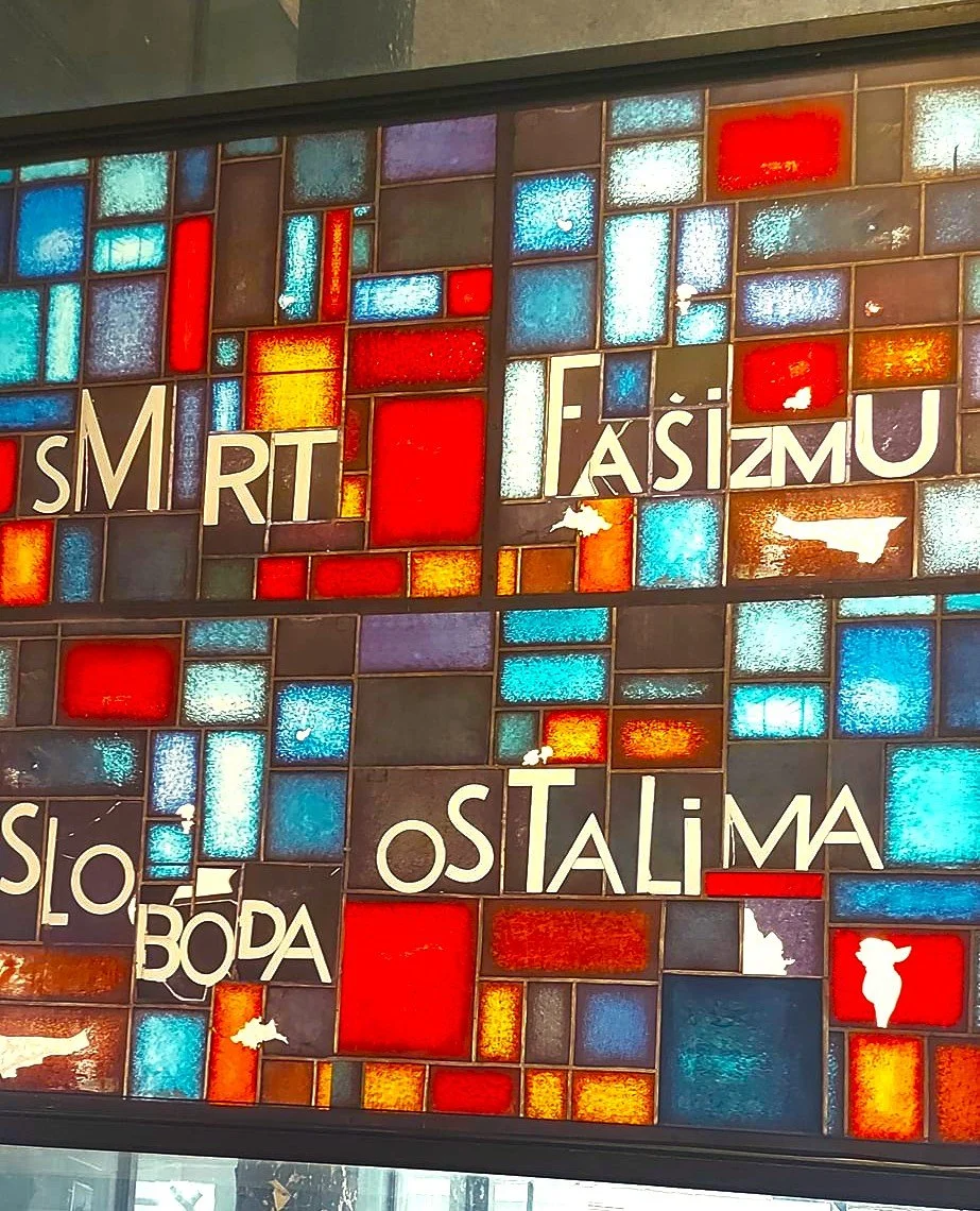 Colorful mosaic wall with Hungarian phrases, including 'SMART TÁRS ikon,' 'Ostalim,' and other partial words, featuring various colored tiles and white puddle-shaped decals.