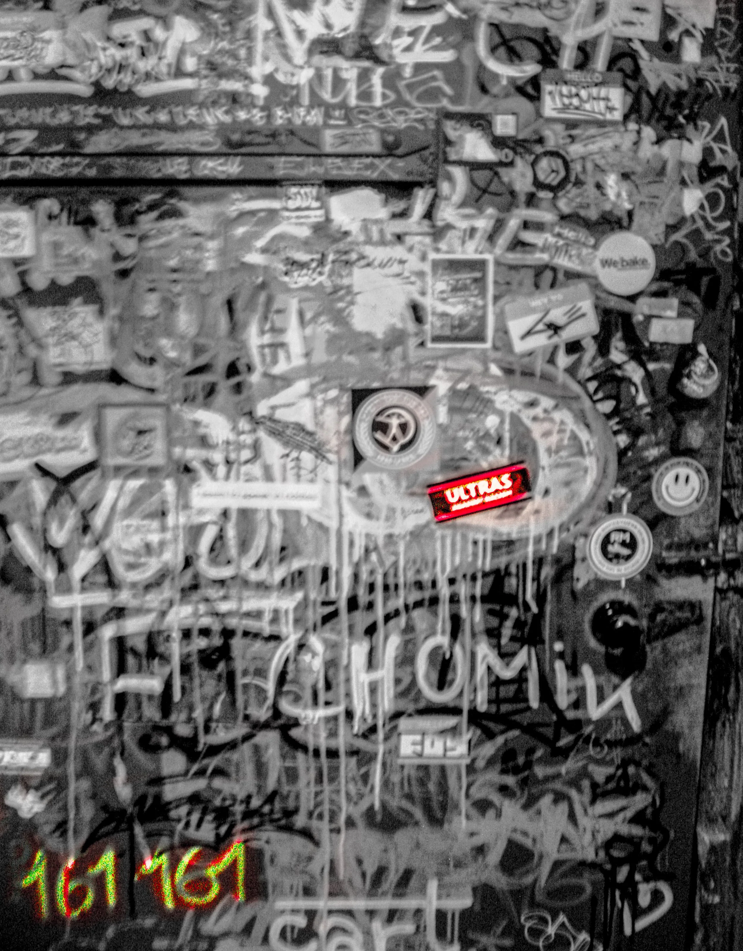 Close-up of a graffiti-covered surface filled with various stickers, tags, and drawings, including a peace sign, smiley face, and words like 'Ultras'.