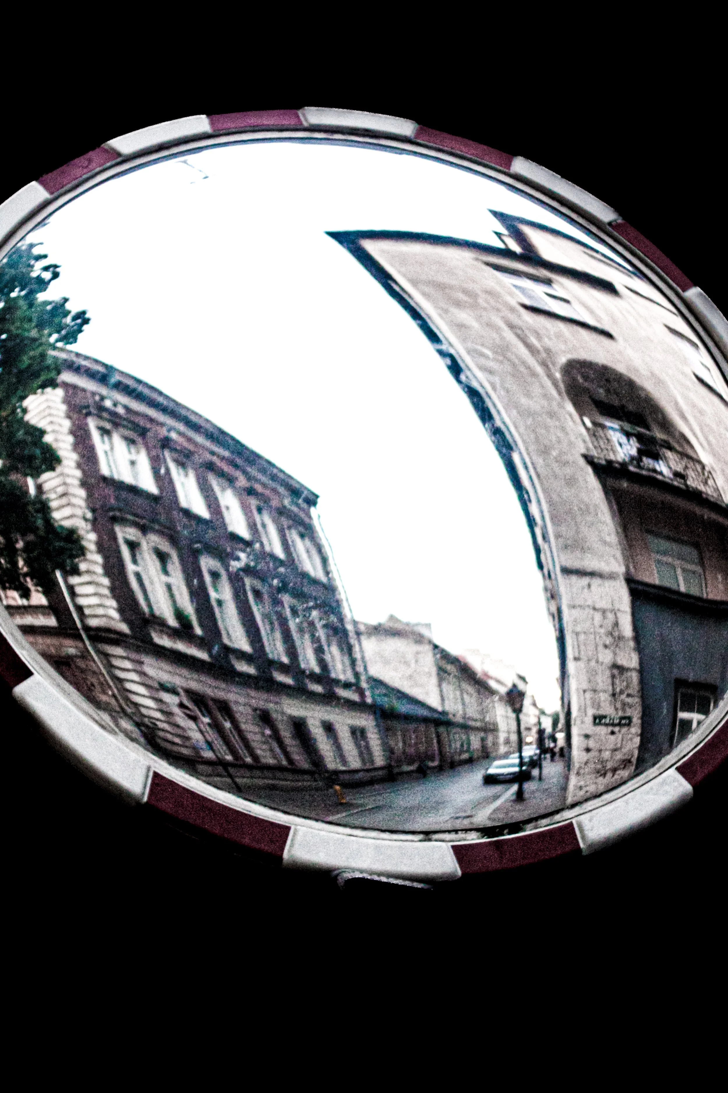 Reflection of buildings and street scene in a convex mirror on a city street.
