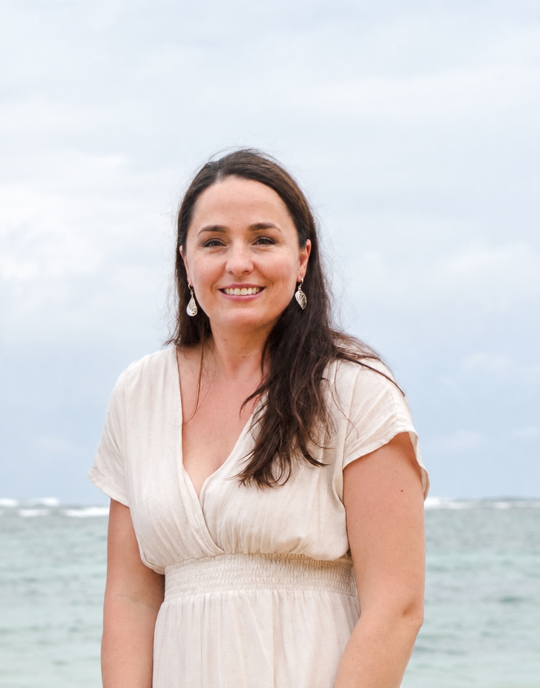 Dee smiling outdoors beside the ocean