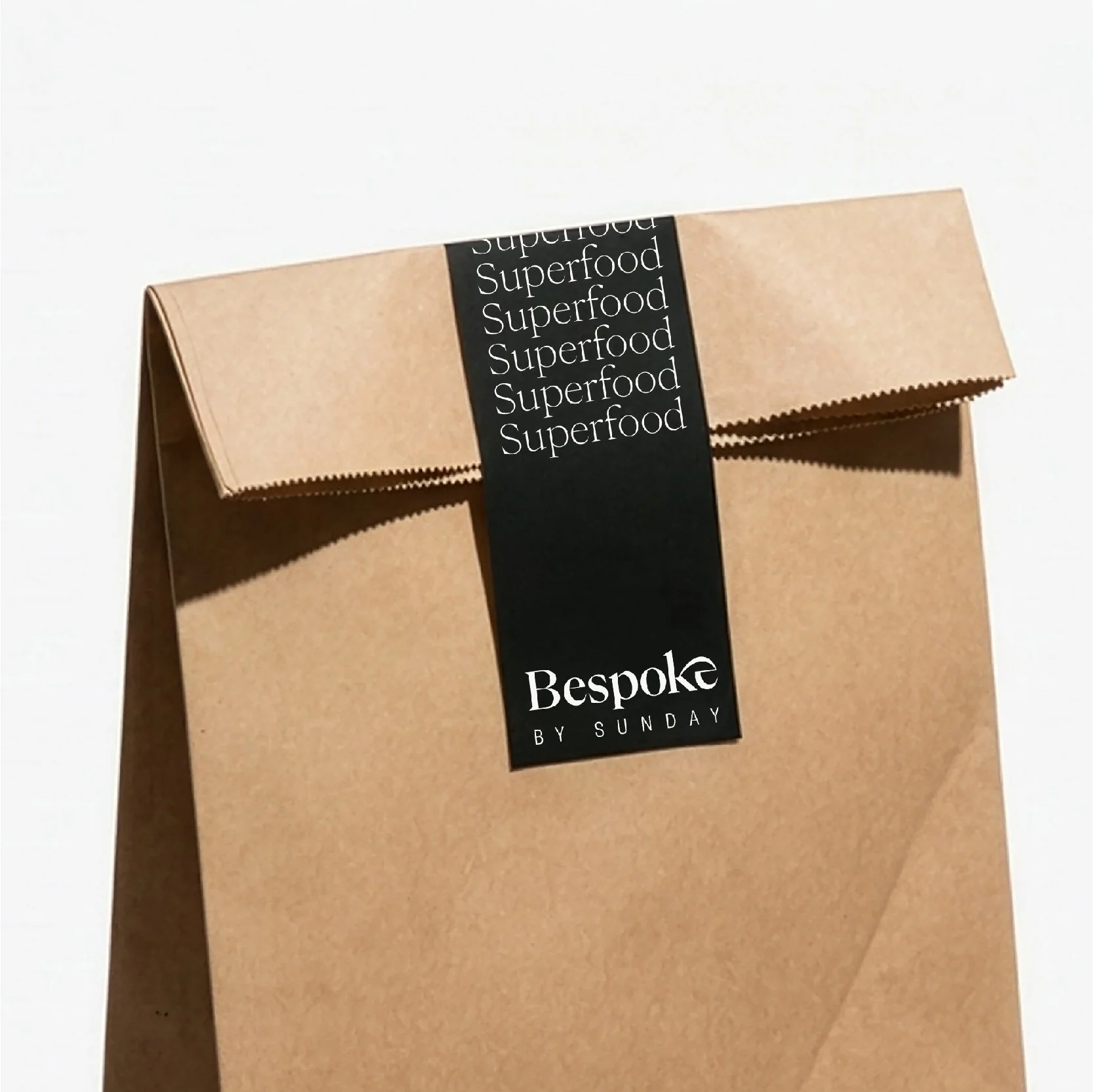 Sac en papier kraft Bespoke by Sunday fermé par une bande noire imprimée « Superfood » et le logo, packaging