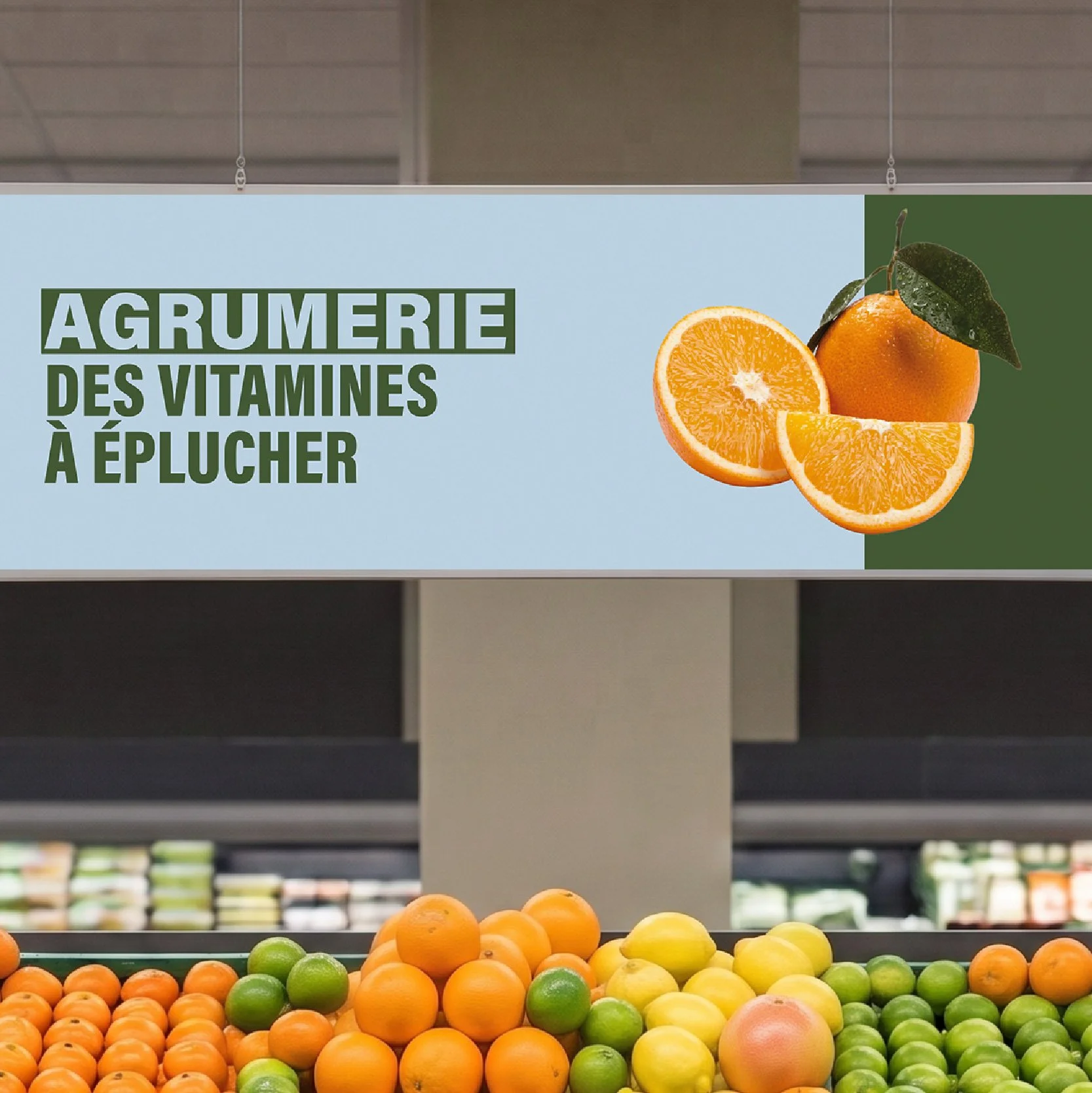 Bandeau de signalétique temporaire Monoprix « Agrumerie, des vitamines à éplucher » au-dessus de l'étal d'agrumes