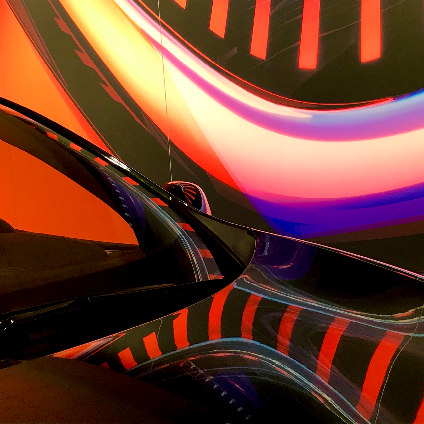 Visuel grand format en concession Renault, traînées de lumière orange, rose et violette reflétées sur la carrosserie