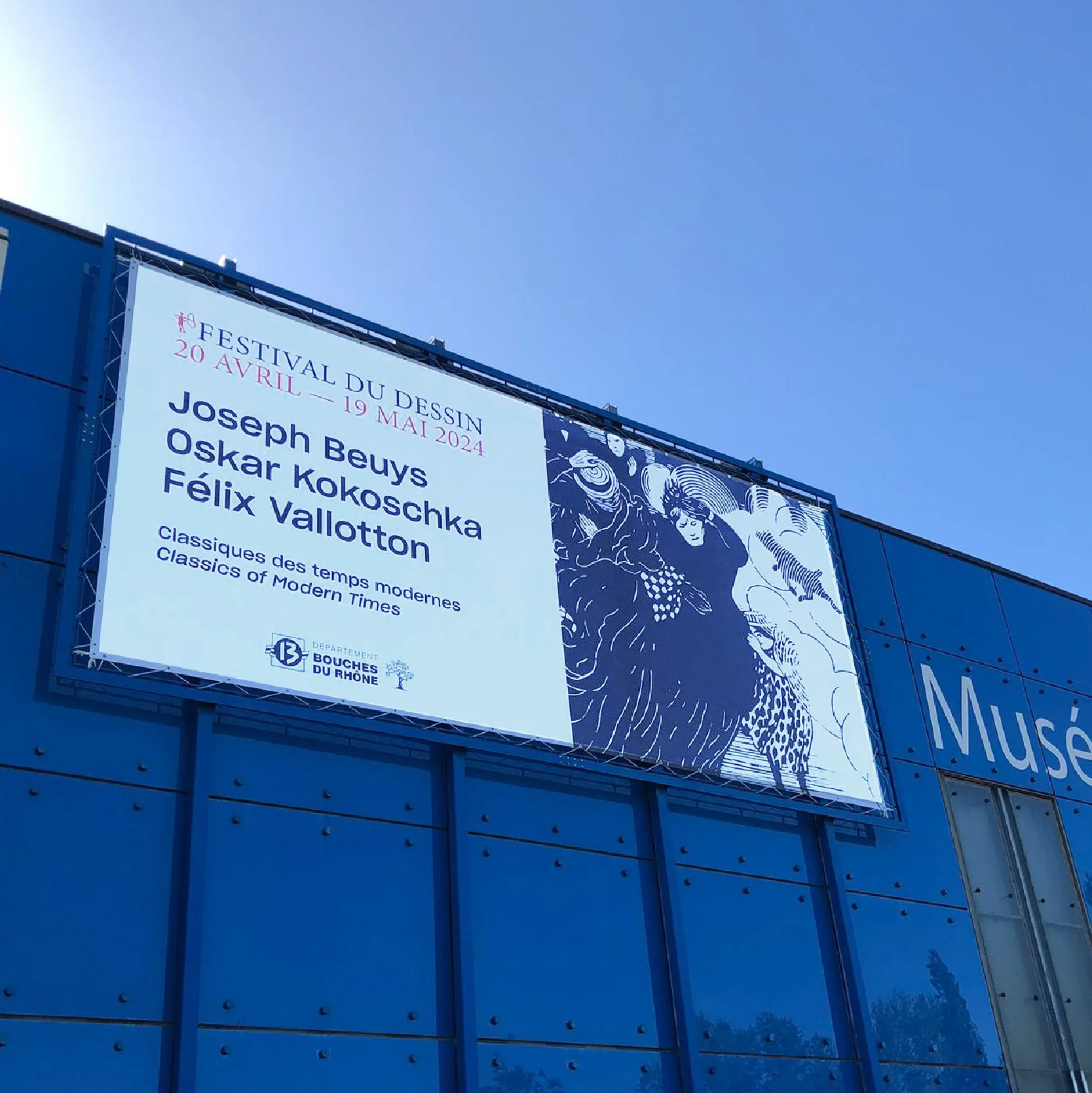 Bâche grand format sur la façade bleue d'un musée, affiche du Festival du dessin « Classiques des temps modernes »