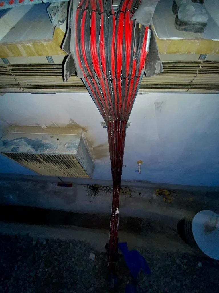 İnşaat alanında, duvara montelenmiş elektrik kabloları. Kablolar kırmızı renkte ve düzenli şekilde yerleştirilmiş.