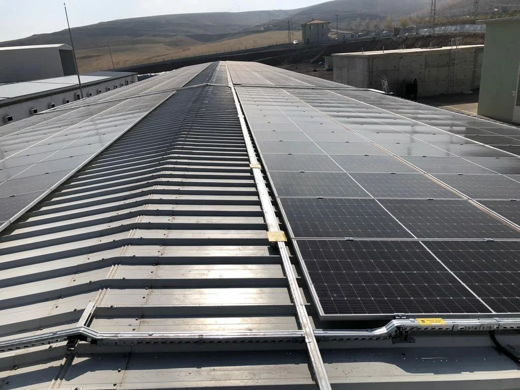 Sağ tarafta güneş panelleri, sol tarafta ise elektrik santrali çatısı üzerinde yer alan güneş panelleri.