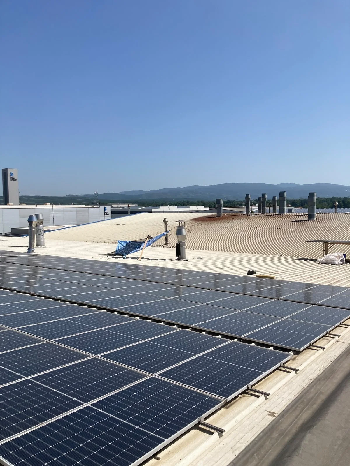 Güneş enerjisi panelleriyle donatılmış bir çatı ve açık mavi gökyüzü.
