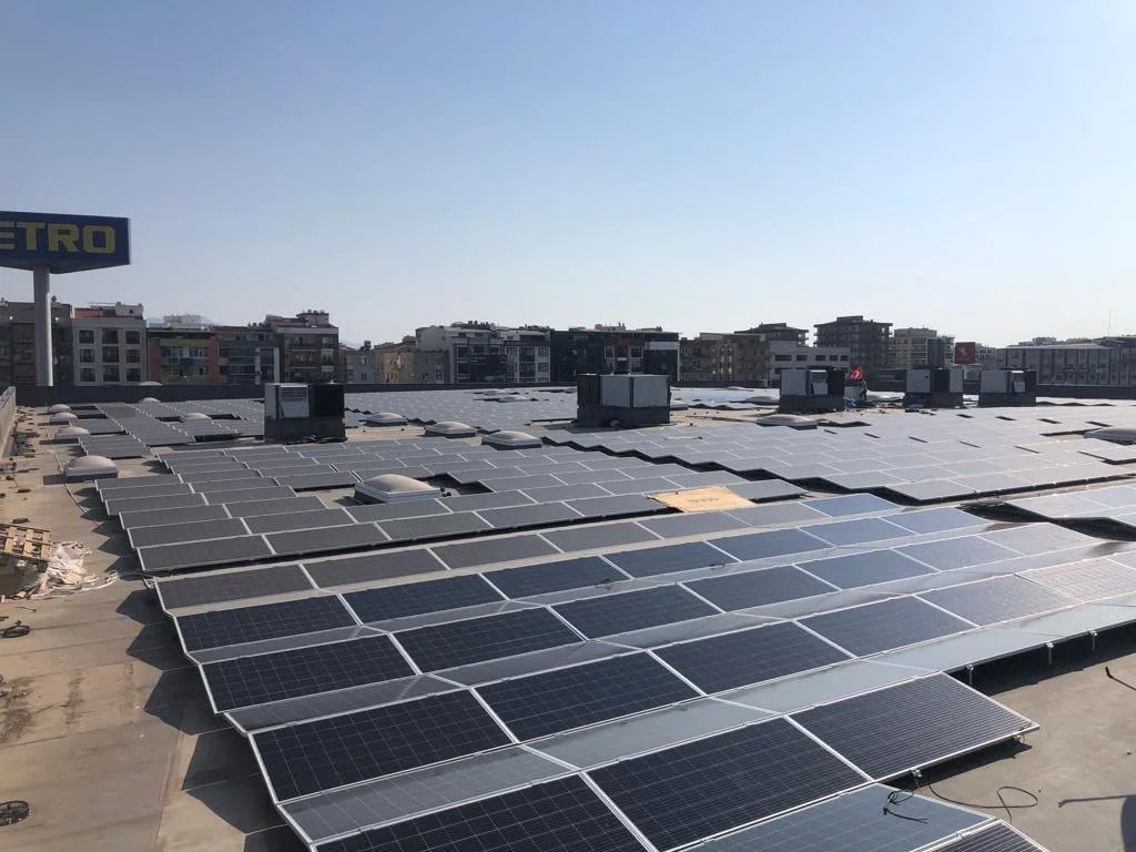 Güneş panelleriyle kaplı çatıda, şehir manzaralı açık hava alanı.