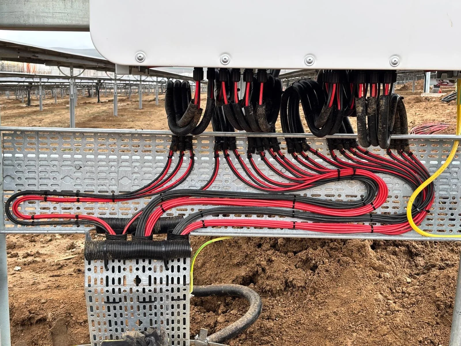 Elektrik kabloları ve bağlantıları dış mekanda, çiçek ekili alanın üzerinde yer almakta.