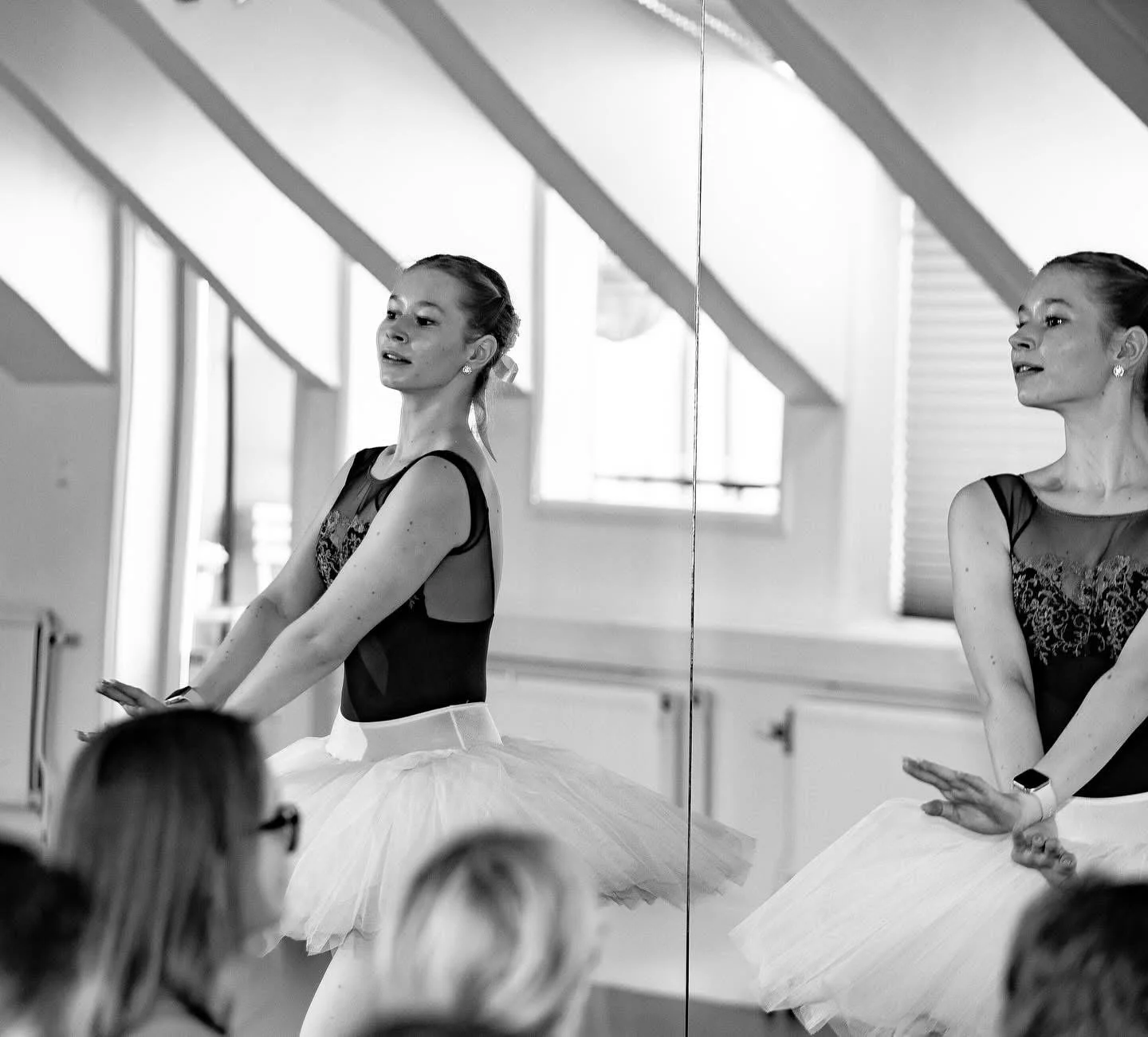 En kvinna i svart ballettklänning och vit tulewrappar som är i en balettstudio, reflekterad i en spegel. Balettcentrum Stockholm