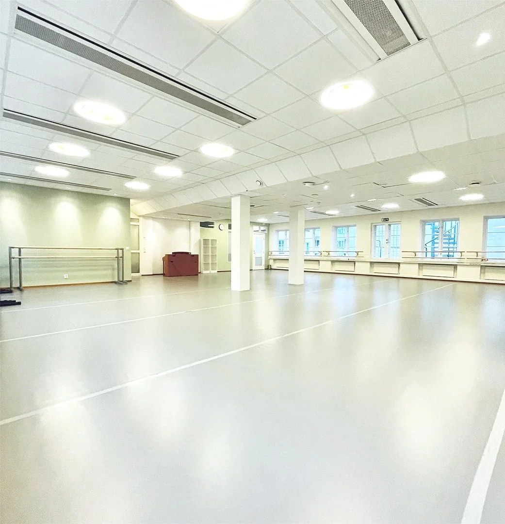 Ett tomt, ljust dansrum med speglar längs väggarna och träbaletter längs fönsterna. Balettcentrum Stockholm