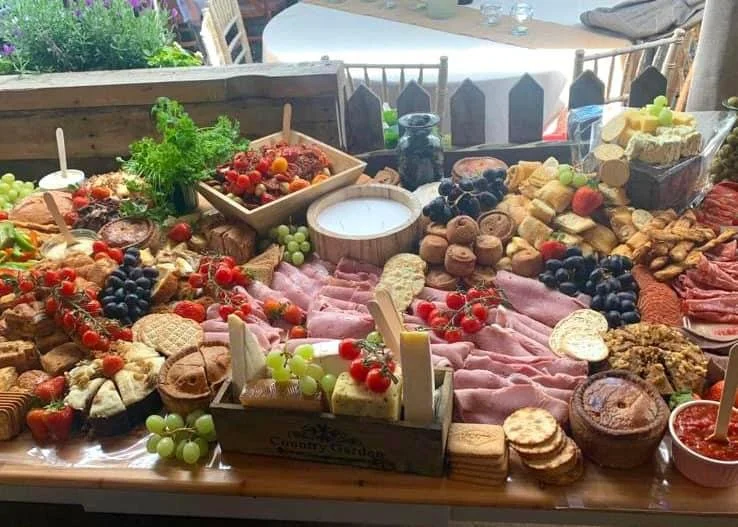 Charcuterie spread with meats, cheeses, fruits, crackers, and vegetables on a wooden table.