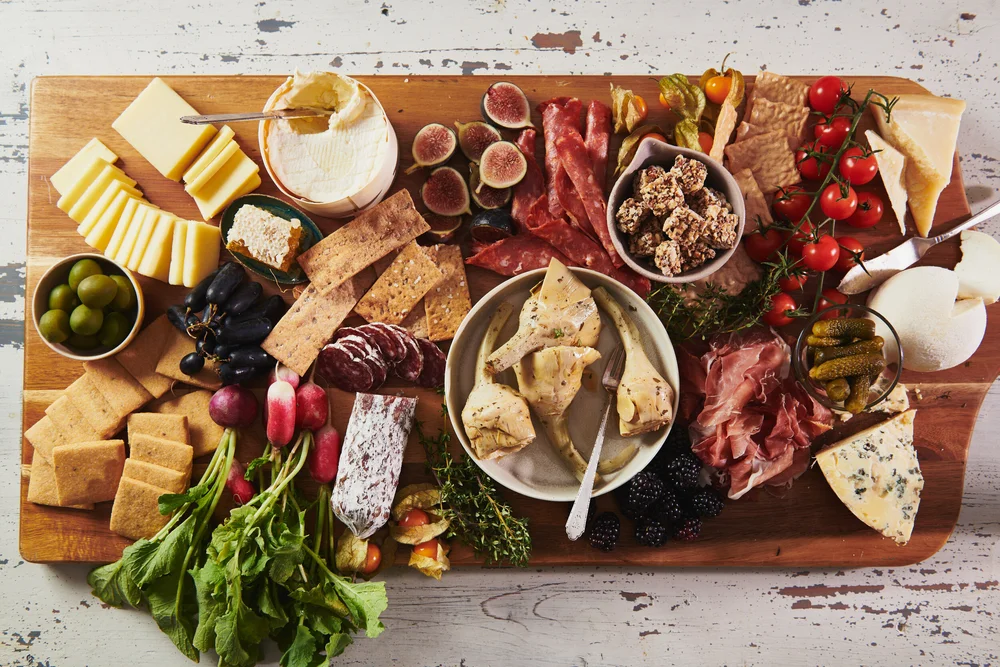 A grazing spread of cheeses, charcuterie, crackers, fruit and olives