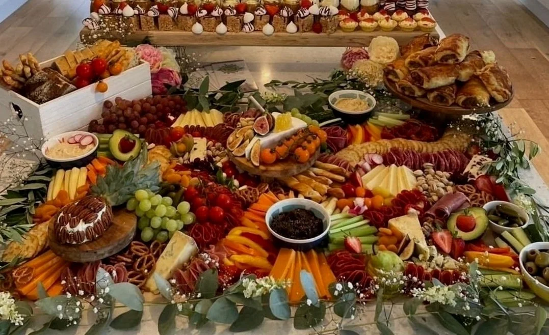 Charcuterie board with fruits, cheeses, meats, and pastries.