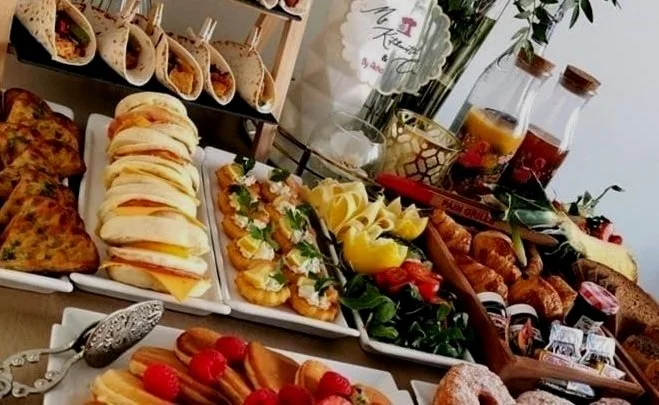 Assorted breakfast buffet with sandwiches, pastries, croissants, fruit, and beverages.