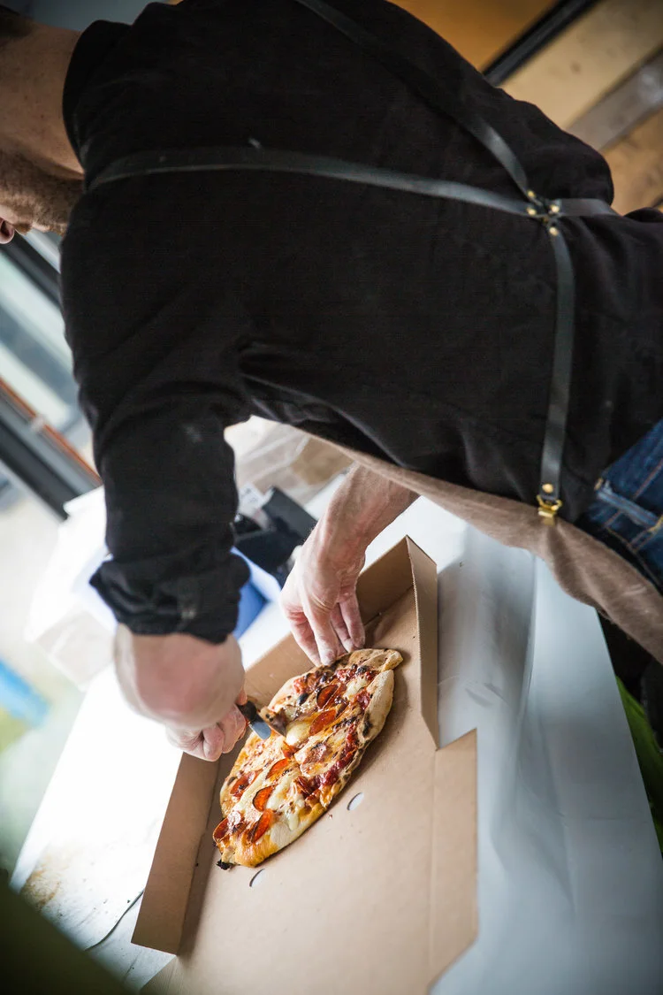 Person cutting pizza in a cardboard box