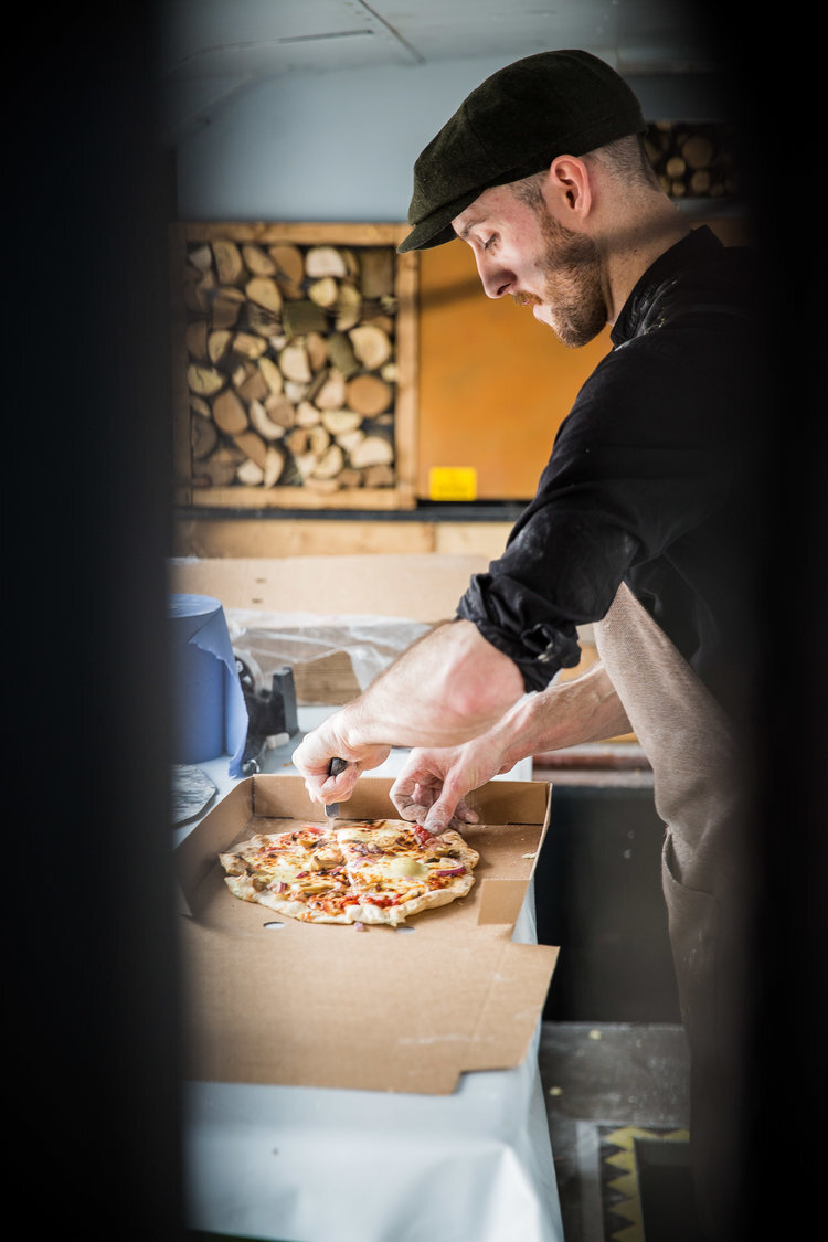 Chef cutting fresh pizza with a knife in a kitchen setting