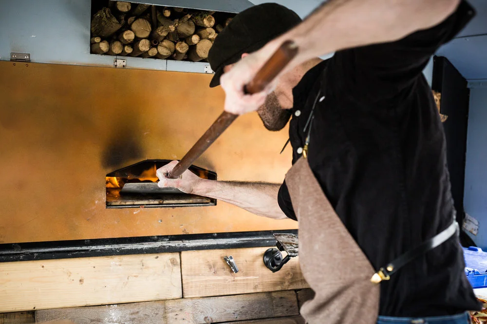 Person baking bread in a wood-fired oven