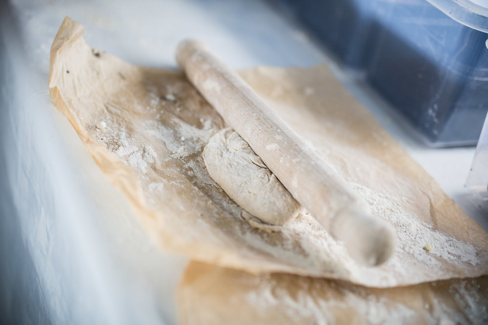 Dough on a floured parchment paper with a rolling pin