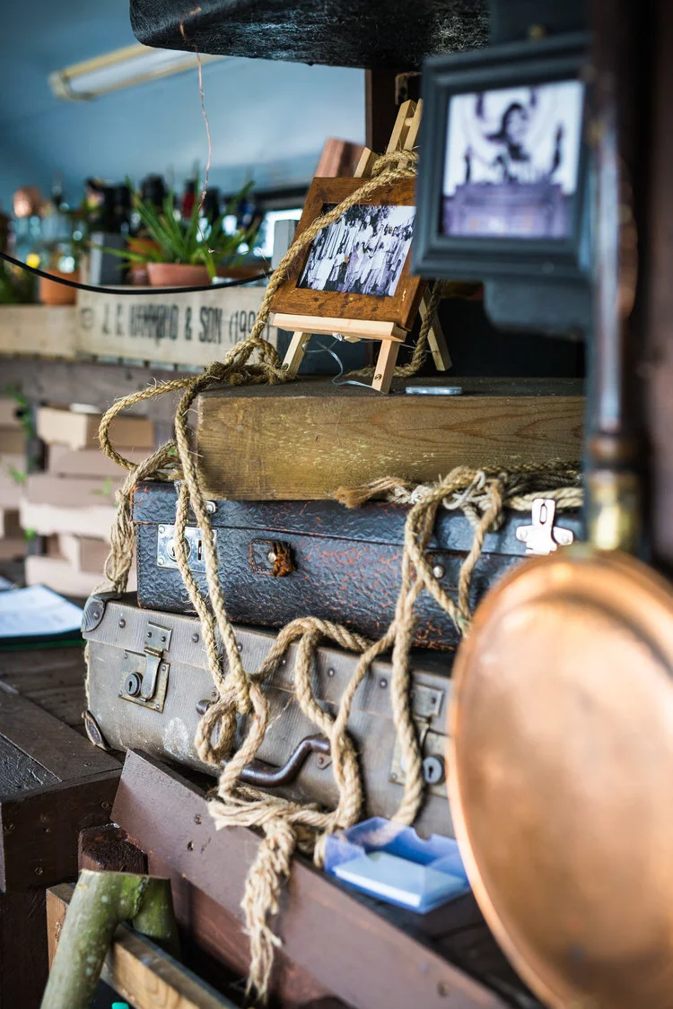 Vintage suitcases with rope, a small easel displaying black and white photos, and rustic decor elements.