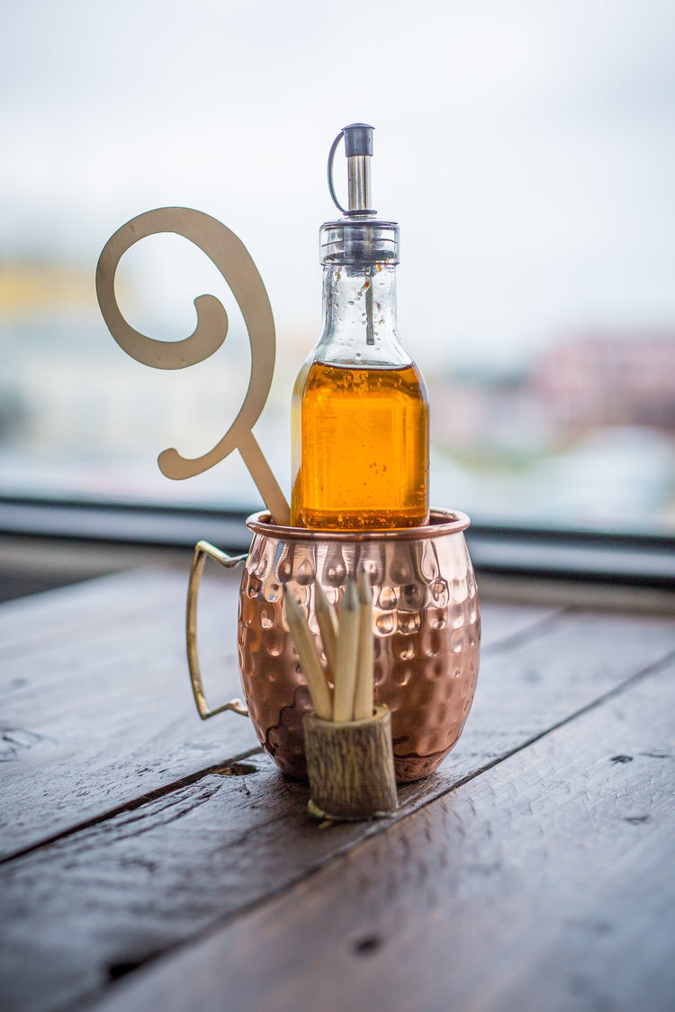 Copper mug with bottle of oil and wooden swizzle stick on table