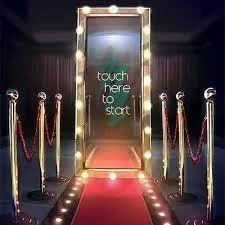 Lighted mirror with "touch here to start" text, red carpet, and velvet ropes