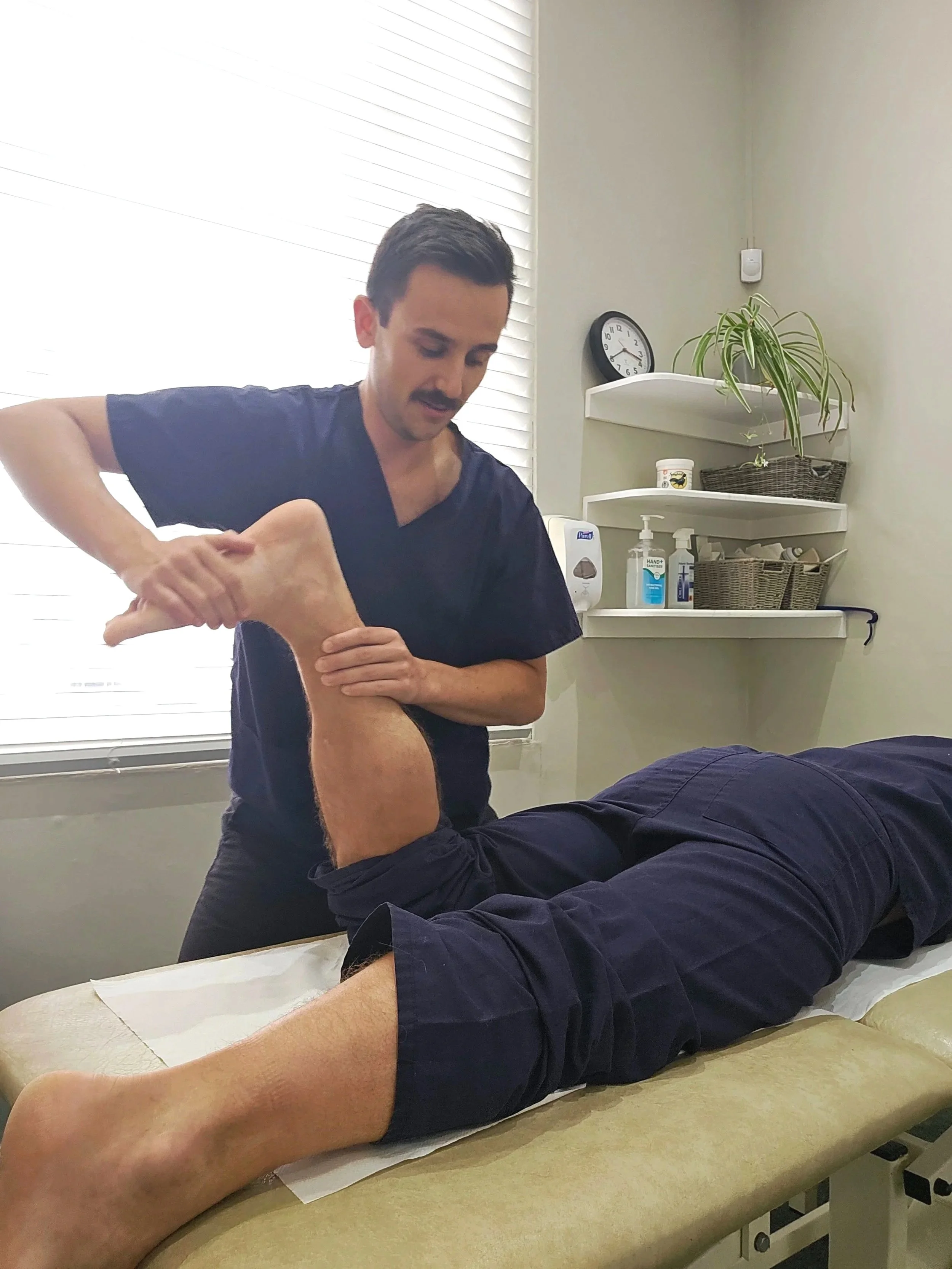 A patient receiving a sports massage from a physiotherapist in a treatment room.