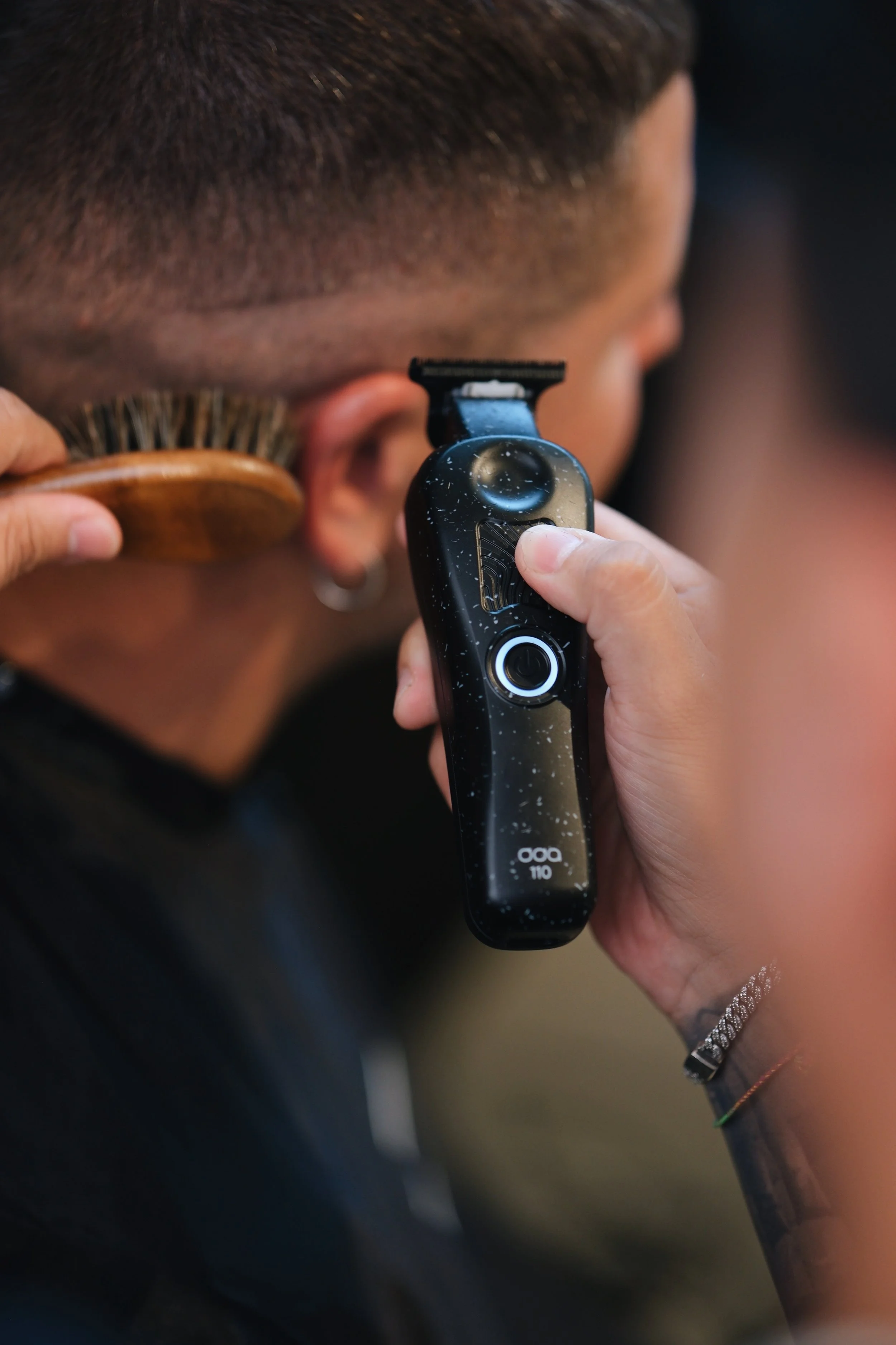 A person getting a haircut with a clipper and a brush.