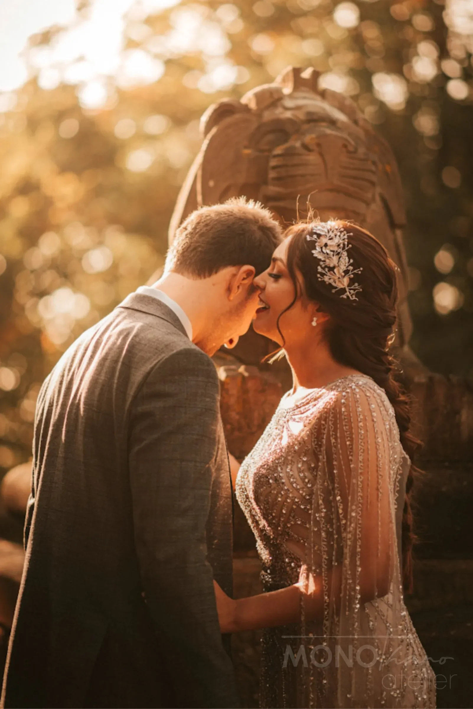 Ein Paar im Hochzeitsoutfit teilt einen intimen Moment im Sonnenuntergang mit goldener Beleuchtung und bokeh-Effekt im Hintergrund.