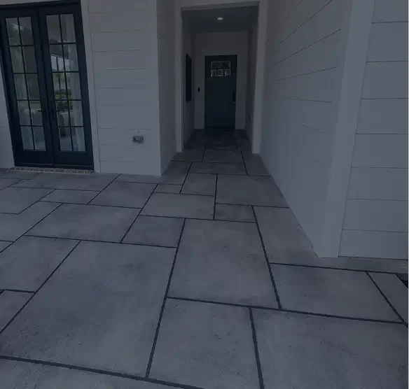 Exterior porch area with large concrete tiles and a front door.