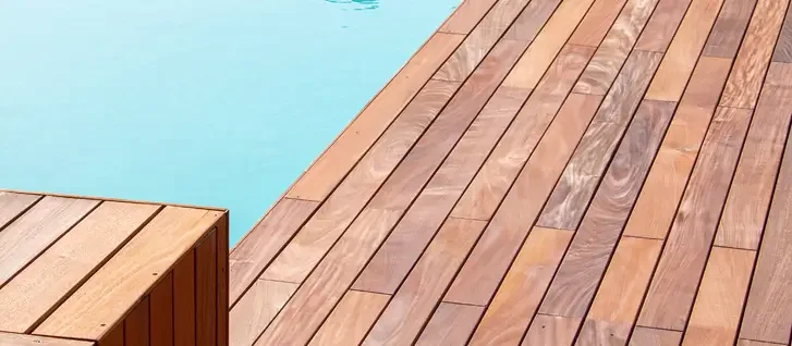 Close-up of wooden deck overlooking a swimming pool.