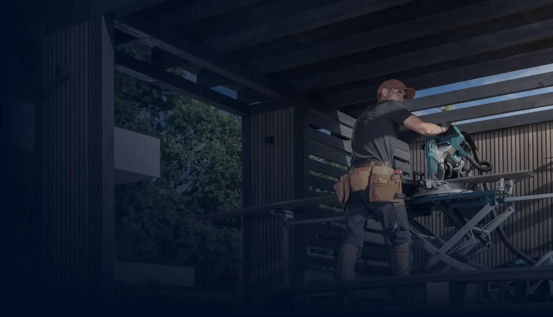A man working with a large power saw on a construction site with wooden beams and a partially built structure.