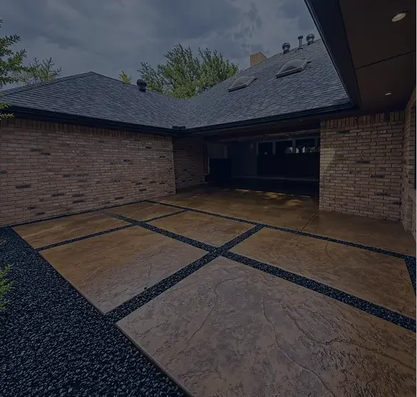 Outdoor patio area with large square stone tiles bordered by black gravel, brick walls, and a roof overhead.