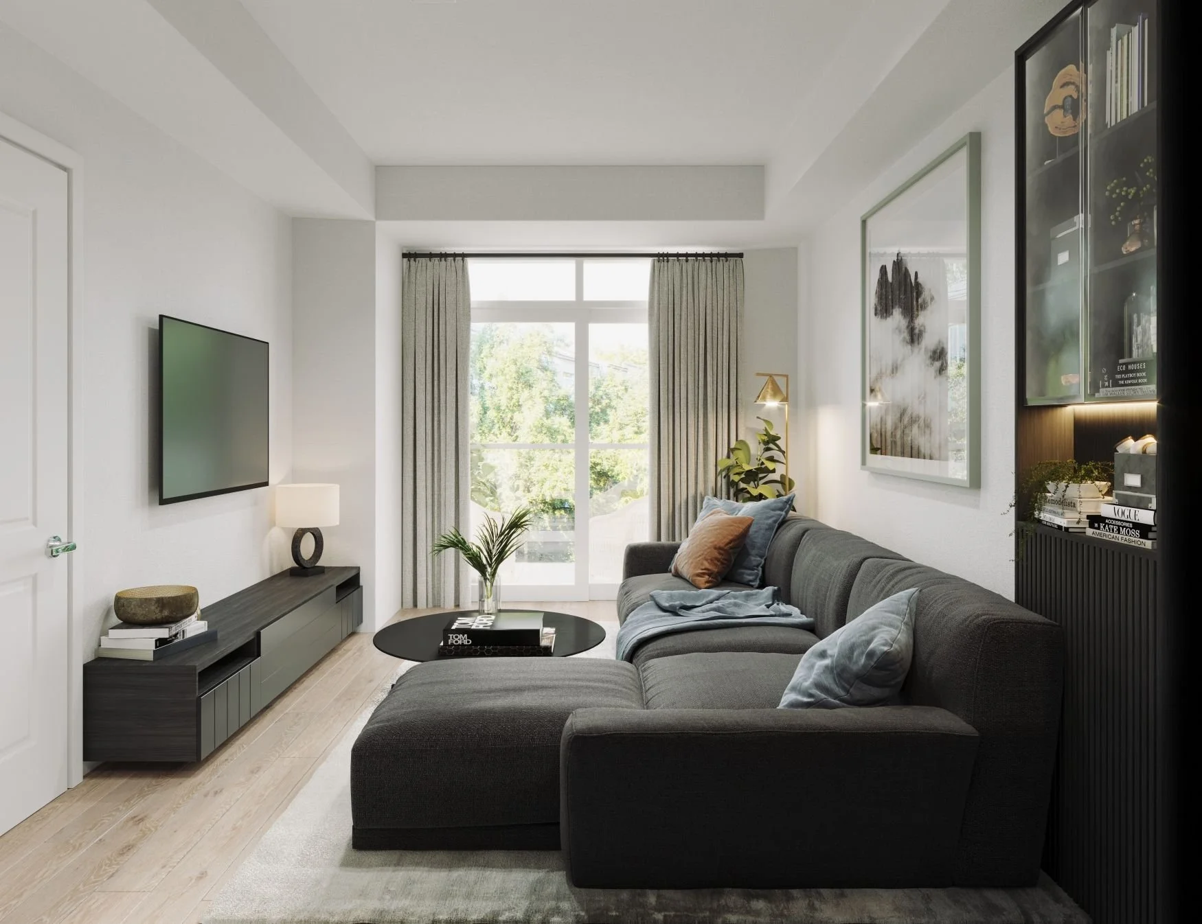 Modern living room with a large gray sectional sofa, a black round coffee table, a wall-mounted TV, a black media console, a large window with beige curtains, plants, artwork on the wall, and a shelf with books and decorative items.