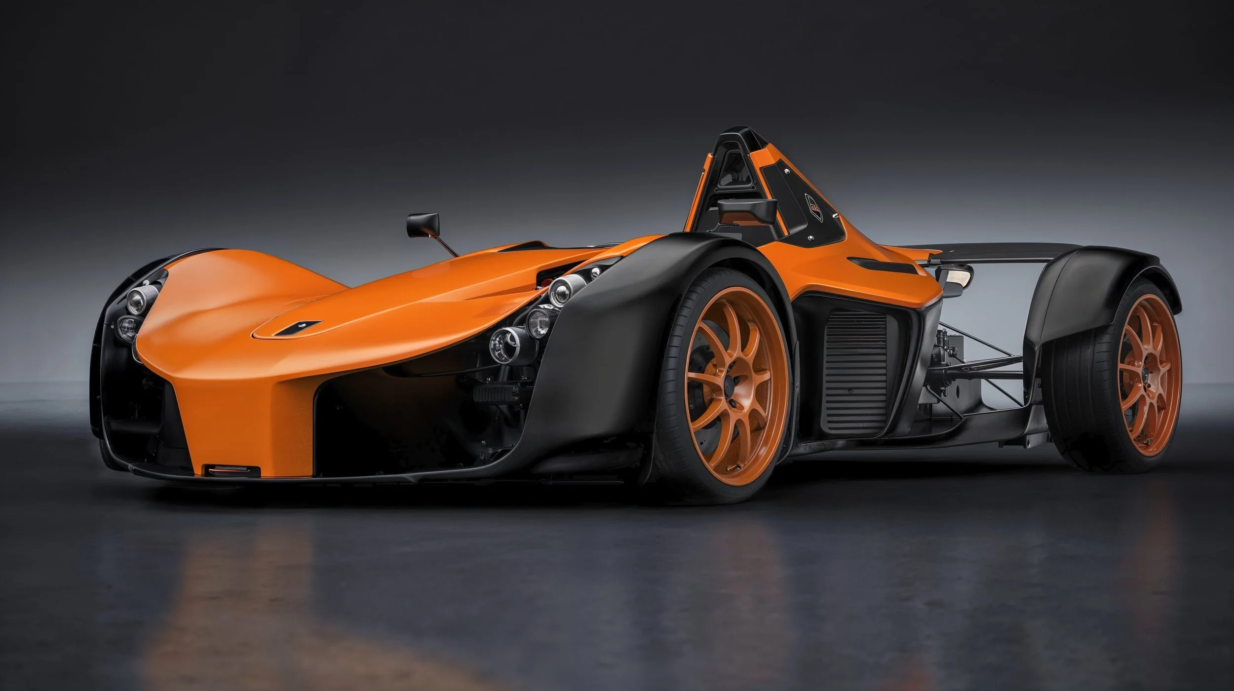 An orange and black open-wheel race car with exposed wheels and aerodynamic design on a dark background.
