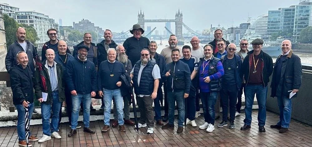 Group of London tour guides gathering outdoors with a open Tower Bridge in London in the background