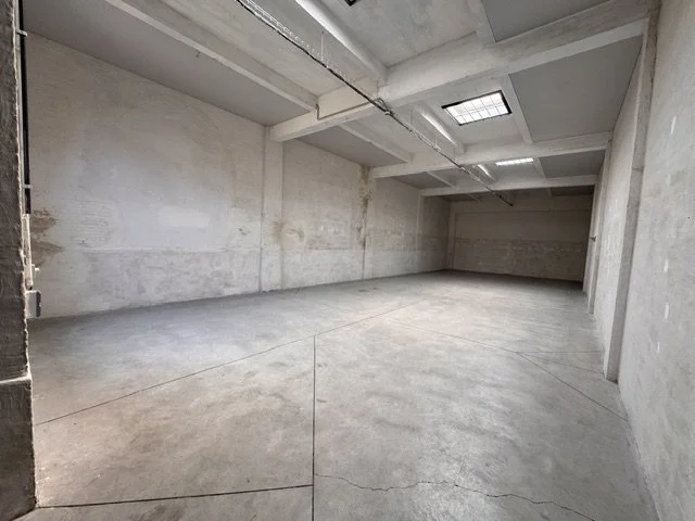 Empty concrete underground parking garage with ceiling lights and skylight.