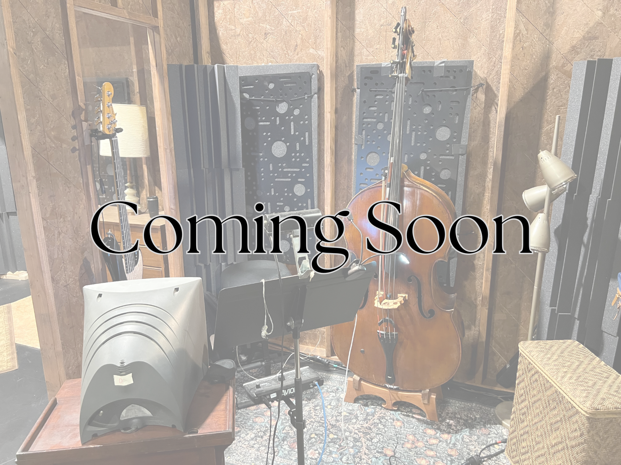 A music studio with two guitars on stands, speakers, soundproofing foam panels, a sheet of paper on one guitar, a lamp, and a woven chair in the corner. The text overlay says 'Coming Soon'.