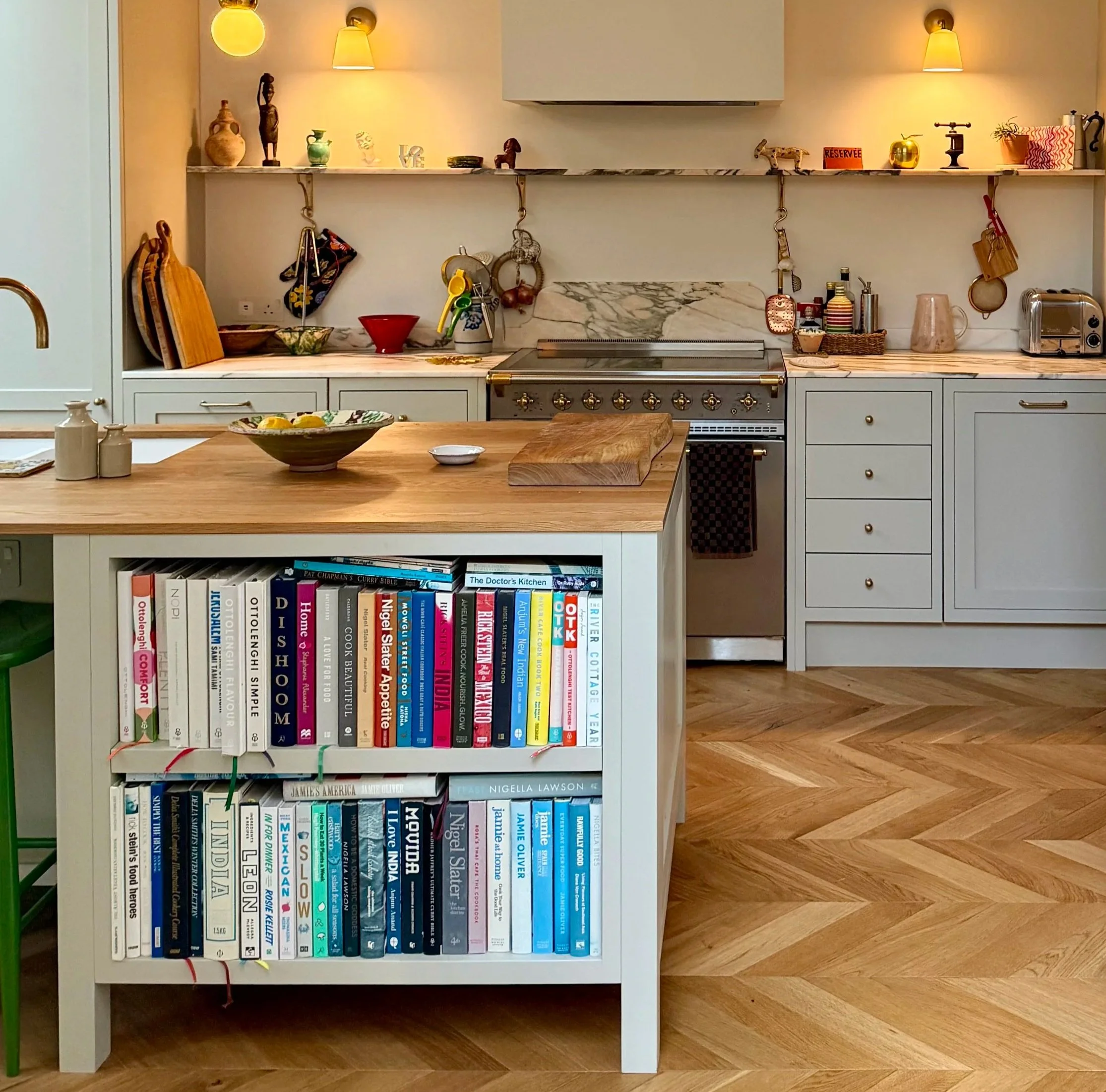 Warm, stylish sharker kitchen with a central island, cookbooks, Rose marble backsplash, range cooker, open shelves