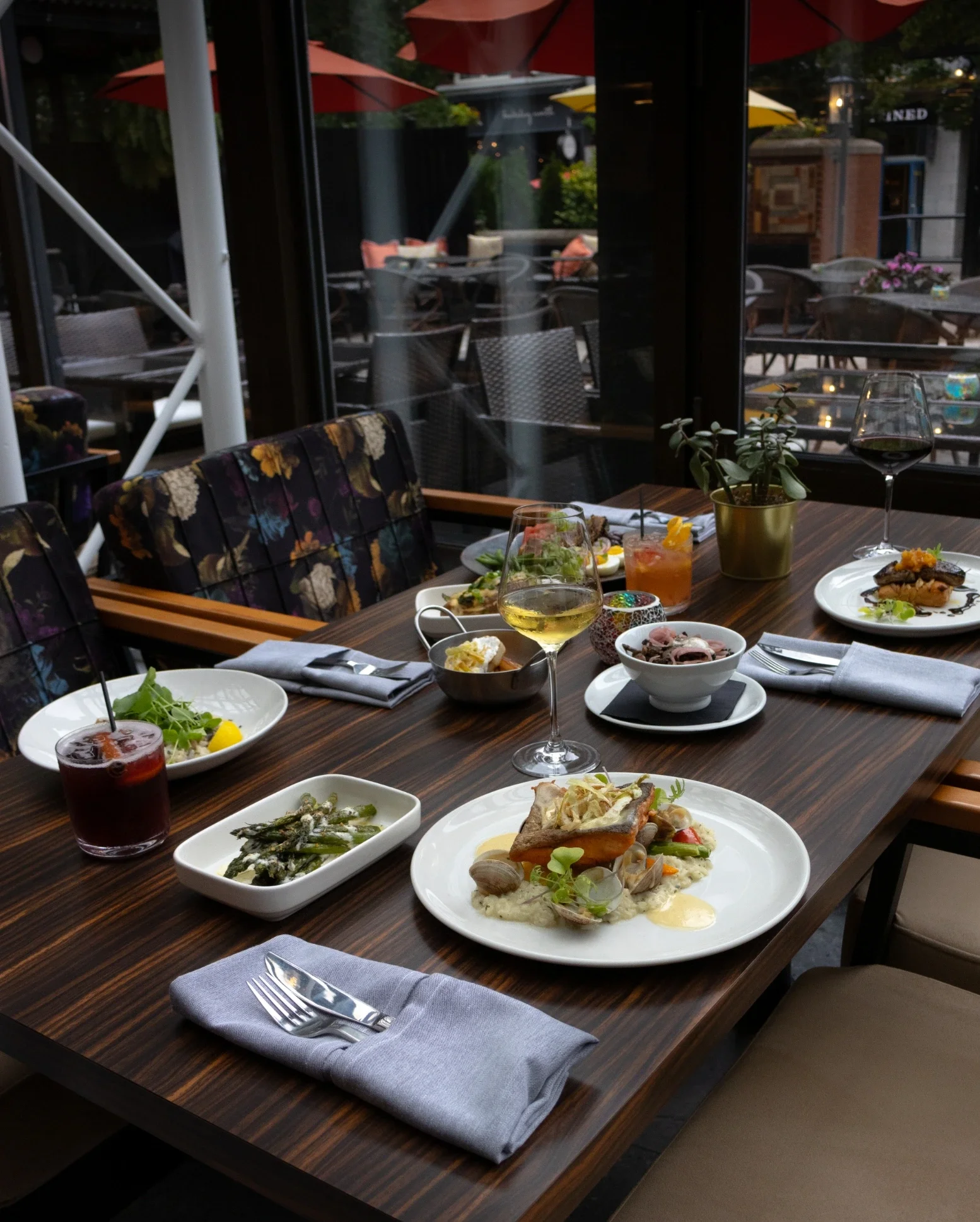 A dining table set with plates of food, glasses of wine at Conversate Steak & Seafood in Hamilton.